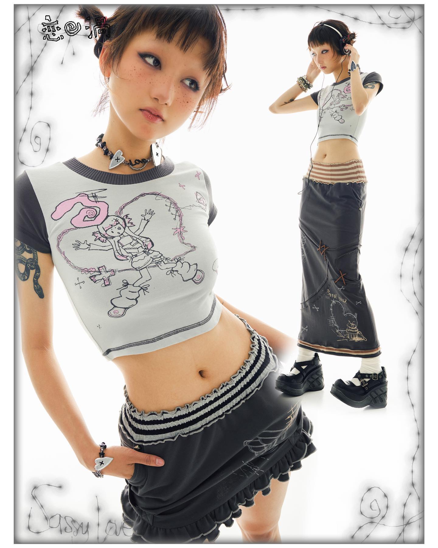 the image showcases two models, each wearing a different outfit yet both aligning with a similar aesthetic of japaneseinspired alternative fashion, possibly harajuku or a similar style.  the main model in the foreground wears a cropped grey graphic tee featuring a cartoonlike illustration and a highwaisted grey mini skirt with ruffles. she's accessorized with a necklace, bracelets, and seems to have small tattoos. the model in the background is wearing a similar style graphic tee, but paired with a longer, dark grey skirt that has distressed details, and is wearing headphones. both models sport platform boots.  the overall vibe is edgy, cute, and incorporates elements of goth, punk, and kawaii styles. the backdrop is plain white with decorative barbedwirestyle graphics. the "sassy love" logo is visible in the bottom left.