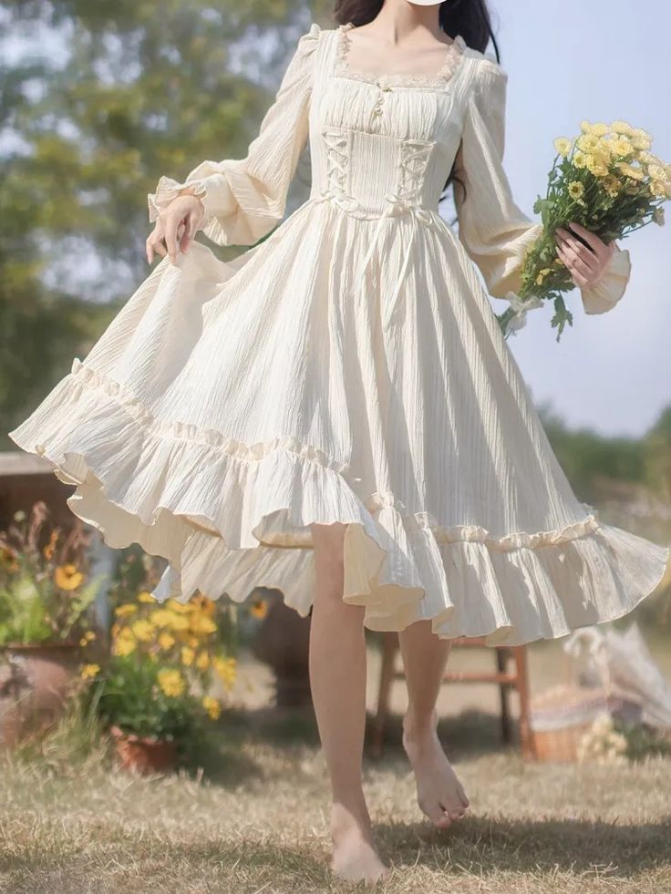 a young woman in a flowing white dress stands in a field of flowers. she is holding a bouquet of yellow flowers in her left hand and the skirt of her dress in her right. the dress is long and flowing, with a ruffled skirt and long sleeves. the woman is barefoot and her hair is down. the lighting is soft and natural, and the overall feeling of the image is one of romance and beauty.