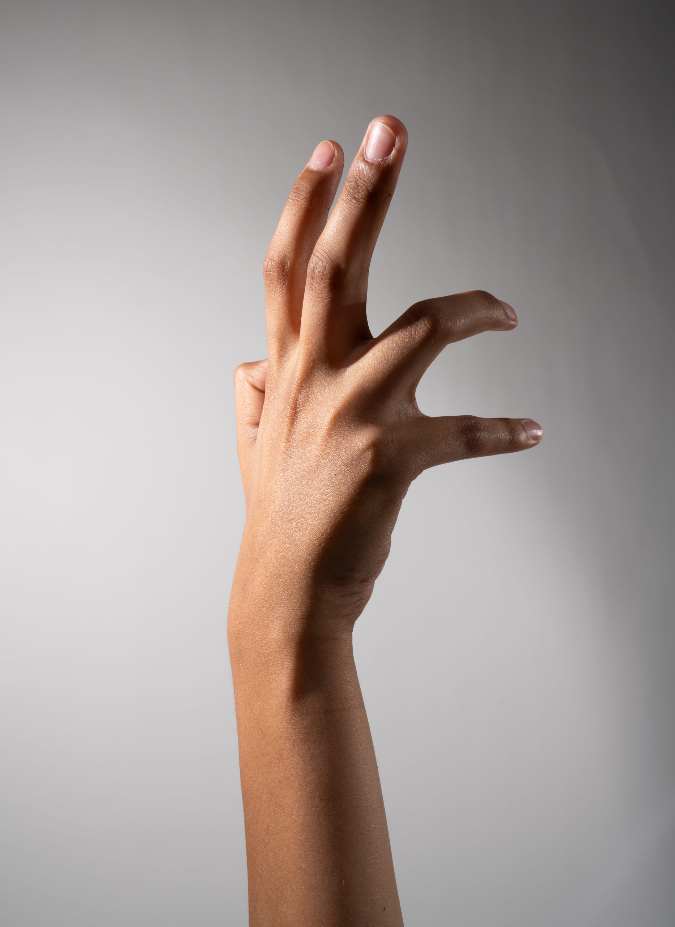 a hand is reaching up with the ring finger and pinkie folded in.