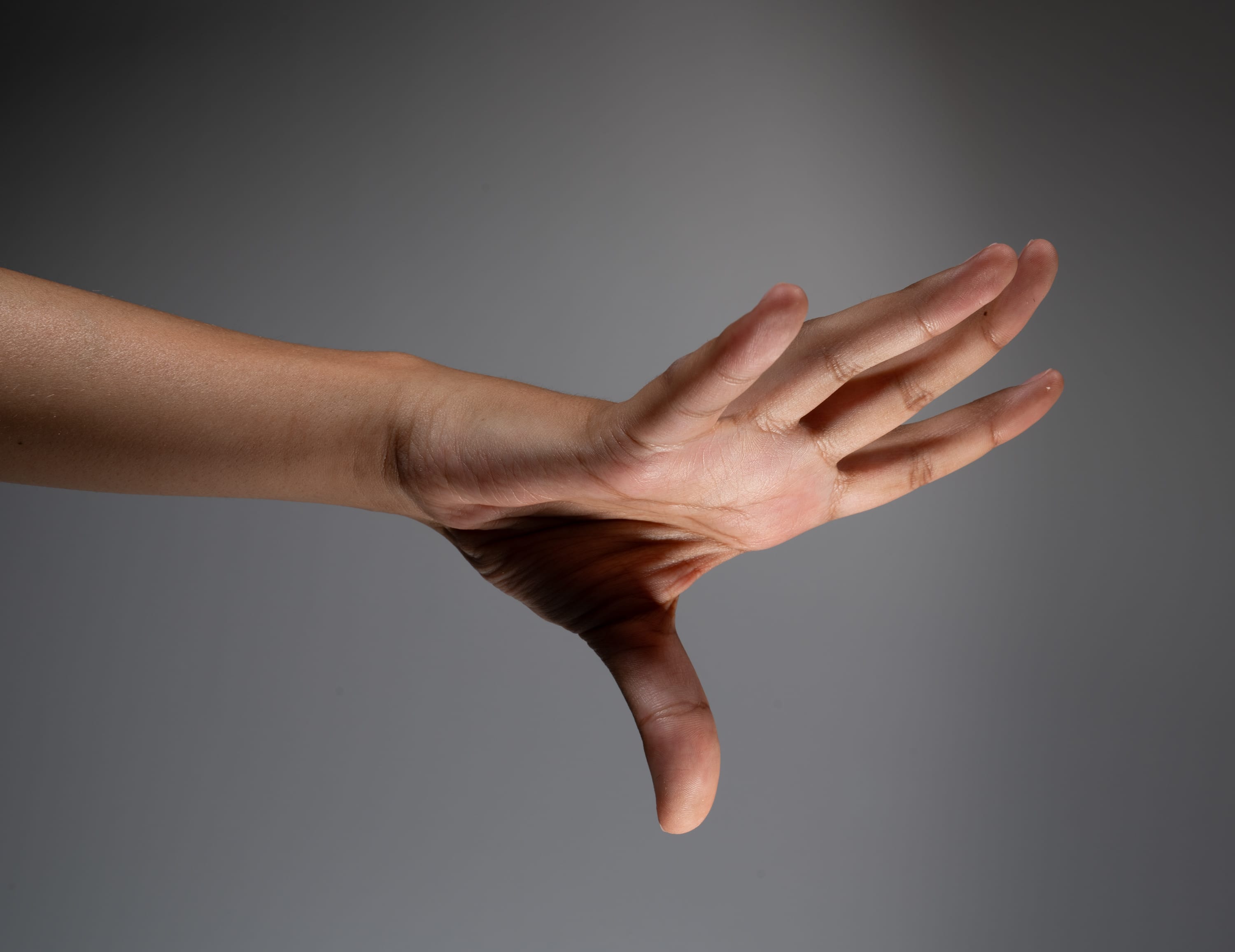 an image of a person's outstretched, sweaty right hand and arm against a gray background.  the spotlight on the hand creates a slight shine on the moist skin.