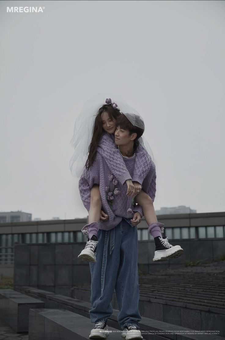 a young couple dressed in fashionable casual wear, the woman in a lavender sweater and veil with her arm around the man