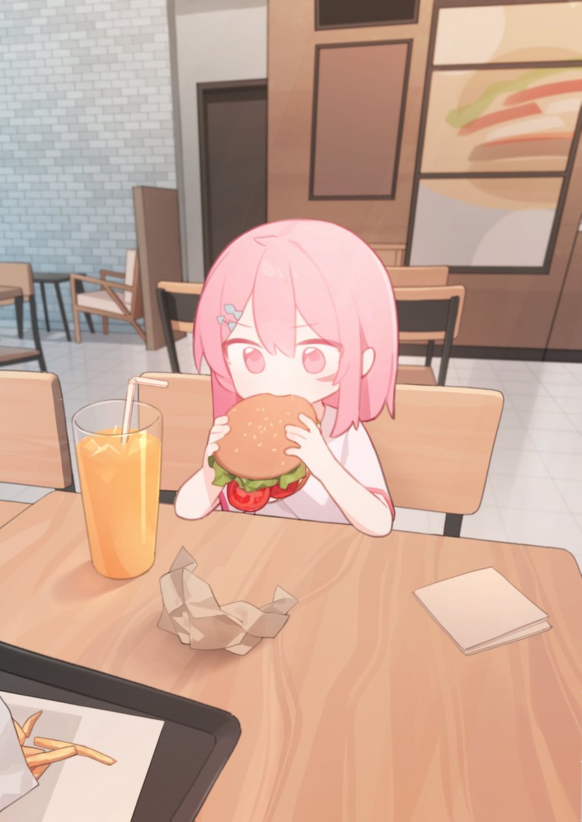the image is a digital drawing of a cute animestyle chibi girl with pink hair eating a hamburger at a cafe. she's sitting at a wooden table with a glass of orange juice next to her. the setting is a casual restaurant with light wood furniture and pastel colors. the overall style is kawaii and cheerful.  there's a crumpled piece of paper on the table, suggesting she's finished part of her meal.  a portion of fries can be seen in the bottom left corner.