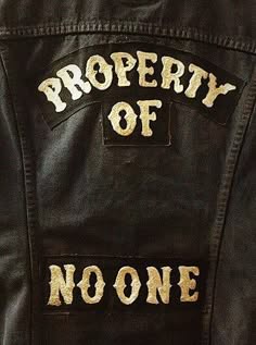 a black leather jacket with a large patch on the back that says "property of no one." the patch is a common symbol associated with motorcycle clubs.