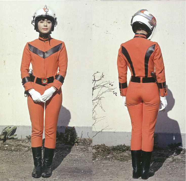 a woman is dressed in an orange spacesuit with a white helmet. she is standing in front of a white wall with her arms at her sides. she looks to the left and right of the image. the image is split into two, so the woman is shown twice.  the woman is wearing black boots and white gloves. there is a black belt around her waist.