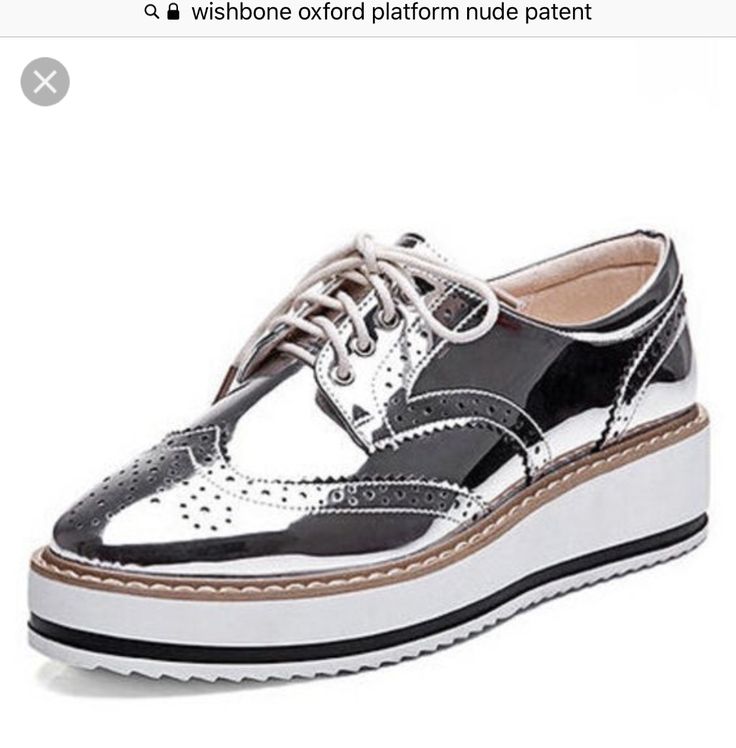 he image shows a pair of women's silver metallic platform oxford shoes. the shoes have a brogue/wingtip design with perforated detailing and a chunky white platform sole.  they appear to be made of patent leather and have a classic oxford style with laces. the shoes are shown from a slightly angled view.  the background is plain white and there's text at the top referring to "wishbone oxford platform nude patent."