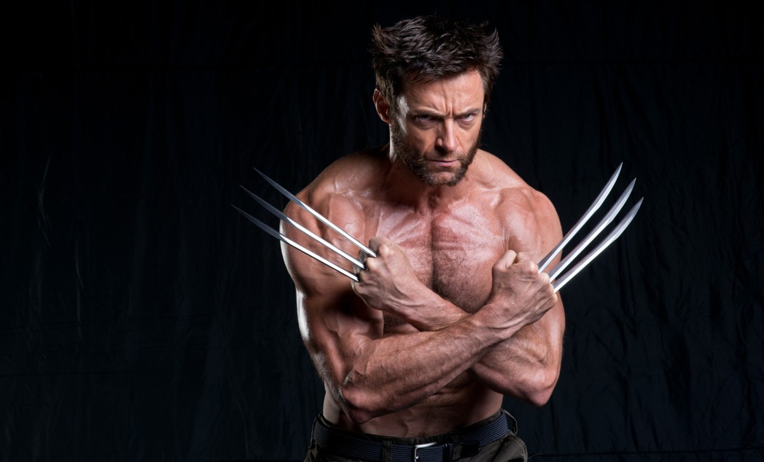 a photograph of hugh jackman as wolverine, an xmen character, standing shirtless with his arms crossed in front of him and his claws out. he has a serious expression and looks muscular. the background is a dark color.