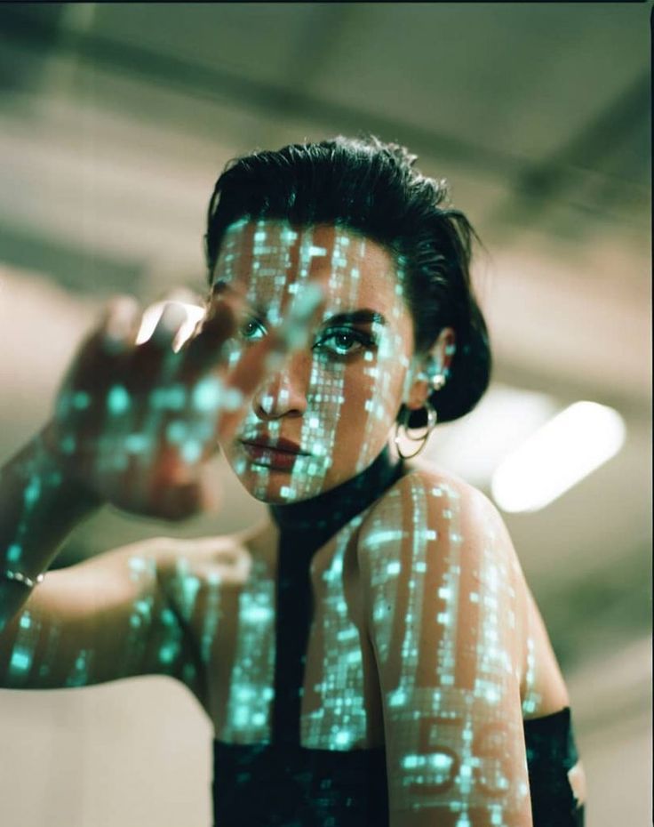 a closeup portrait of a young woman with a futuristic and cyberpunk aesthetic. her face is illuminated by a bright neon light, casting a glowing pattern across her skin and creating a digital, almost ghostly appearance. she is wearing a dark, sleek outfit with a modern and stylish design. the image evokes a sense of mystery and intrigue, suggesting a world where technology and human identity intertwine.