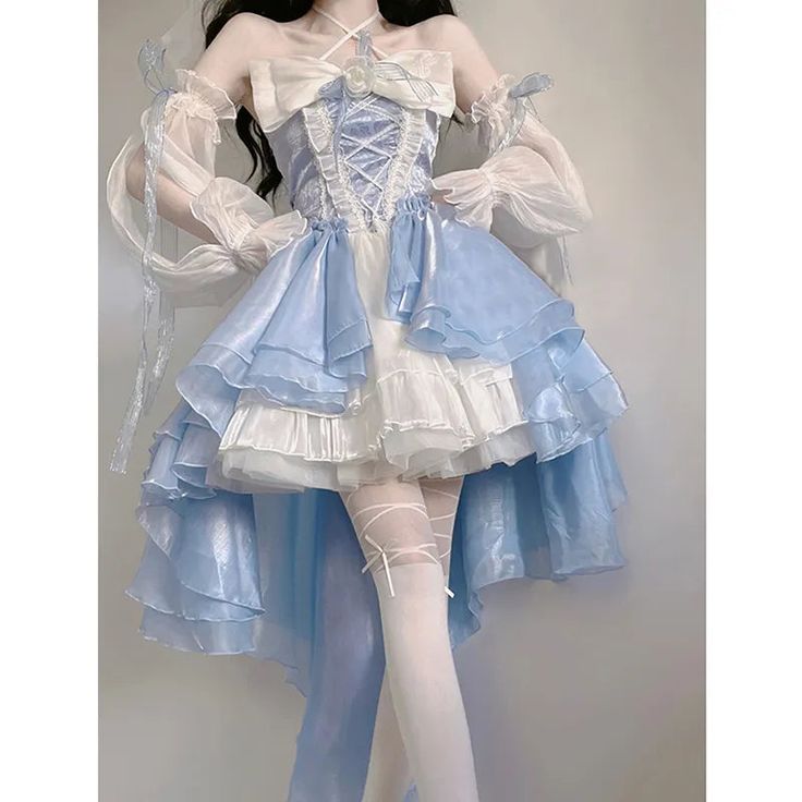 a woman is wearing a light blue and white lolita dress. the dress has a corset bodice with a laceup front and a layered skirt with ruffles. the woman is also wearing white gloves and white tights. she is standing in front of a white wall.