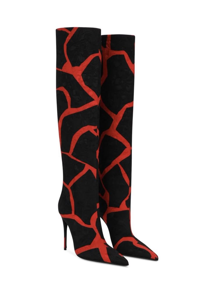 two kneehigh stiletto heel boots are placed side by side against a white background. the boots are black with a bold red, cracked or branched pattern.
