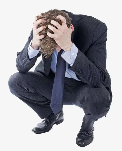 a man in a suit is sitting on the floor with his head in his hands, looking distressed and overwhelmed. he appears to be experiencing feelings of sadness, anxiety, or frustration. the image captures a moment of vulnerability and emotional turmoil, emphasizing the weight of his situation.