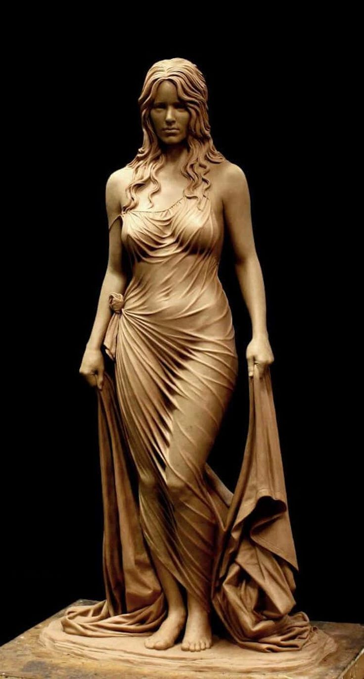 the image showcases a meticulously crafted clay sculpture of a woman. she stands gracefully, her body swathed in a flowing, intricately detailed dress that drapes and folds realistically. the studio lighting highlights the texture and form of the sculpture, emphasizing the artist's skill in capturing the nuances of the female figure.  the background is a stark black, which further draws attention to the sculpture.