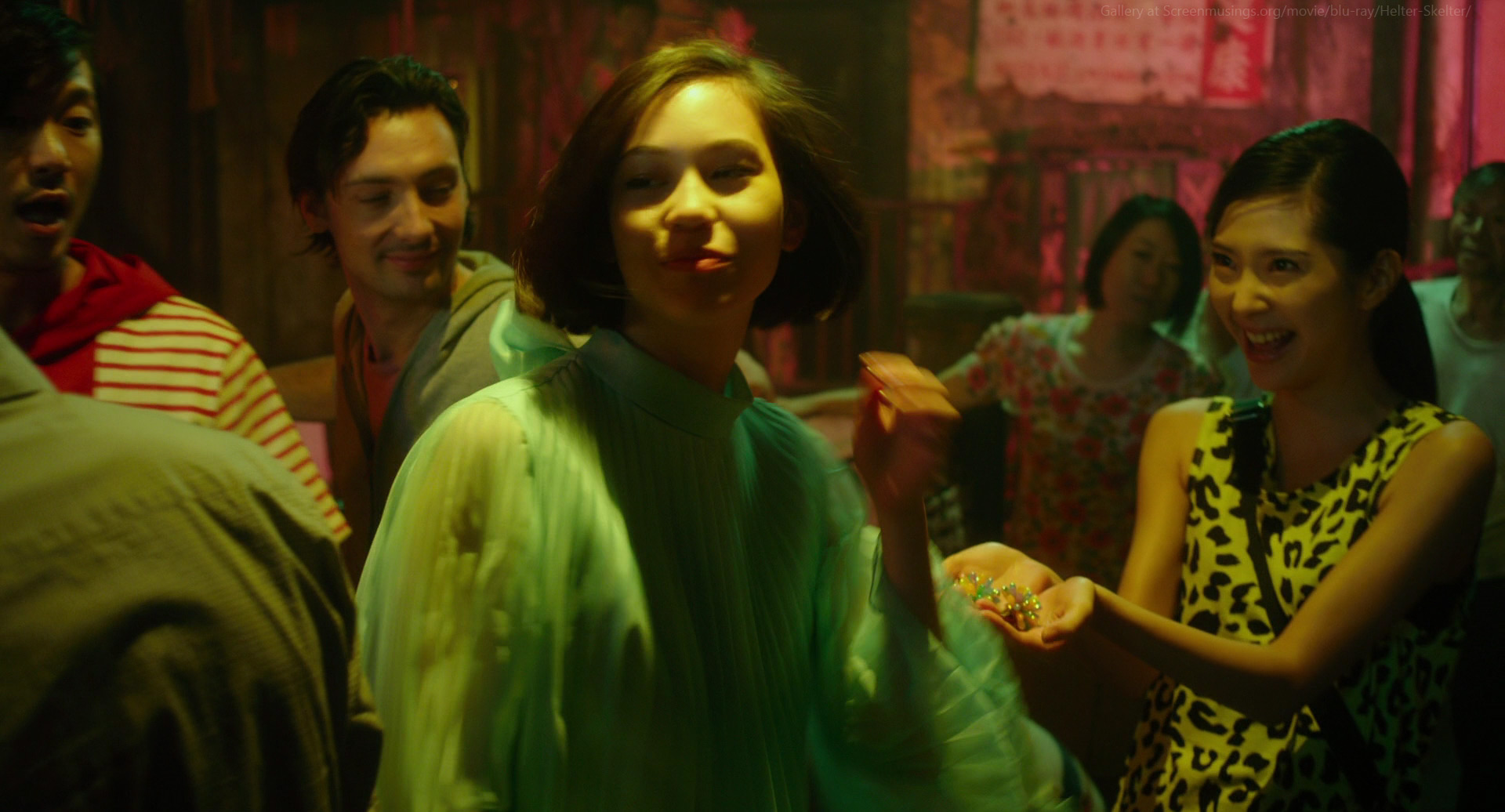 a group of young people are seen standing together and having a fun night out. they're all smiling and laughing, and it looks like they're enjoying themselves. the scene is set at night, with the city lights in the background.