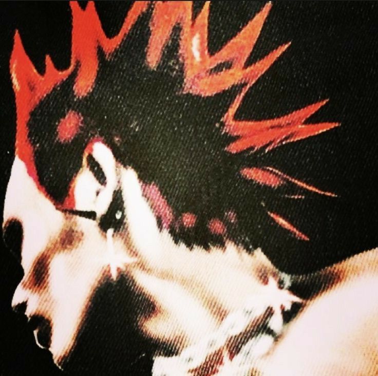 a closeup of a person with a vibrant red mohawk hairstyle, looking like a punk rocker with a rebellious attitude. the image emphasizes the sharp, spiky nature of the mohawk and the person's cool, alternative fashion style.