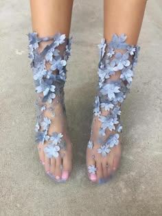 this image showcases a woman's feet adorned with exquisite floralembellished socks. the socks feature delicate blue flowers intricately woven into the sheer fabric, creating a stunning visual effect. the shoes themselves are not visible, only the socks. the woman's feet are posed in a slightly angled position, highlighting the floral designs and the elegant nature of the accessories.