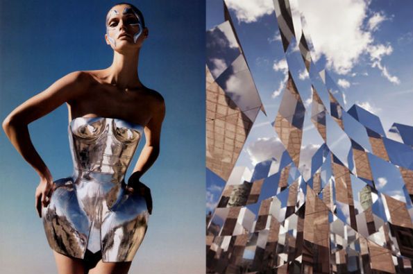 a woman wearing a silver futuristic dress stands in front of an abstract metallic structure with reflecting glass panels, showcasing modern fashion and architecture.