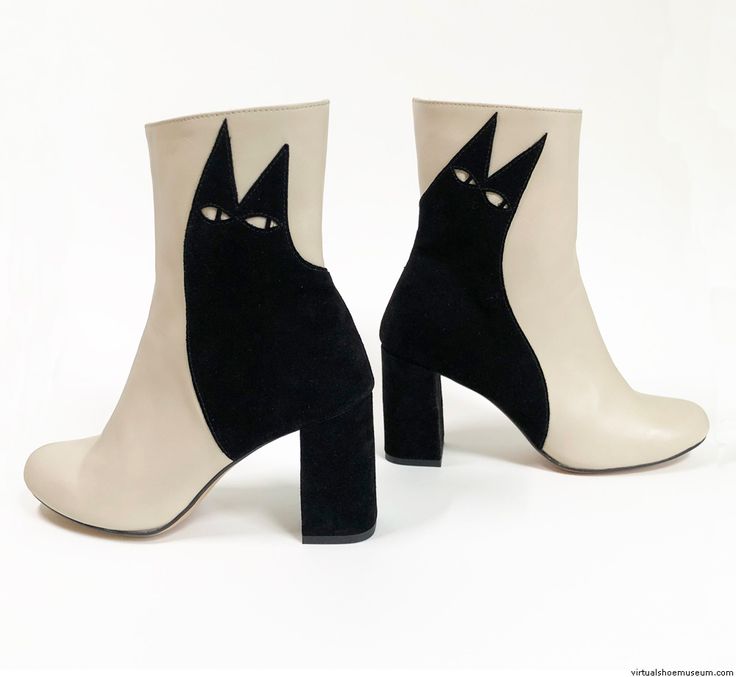 the image showcases a pair of women's ankle boots.  the boots are a twotone design, featuring creamcolored leather on one side and black suede on the other.  a distinctive feature is the black suede cutout design on the cream side, shaped like a stylized cat's face.  the boots have a chunky block heel.  the image is taken against a simple white background, highlighting the design details of the footwear. one boot is positioned slightly forward and angled for a better view. the "virtualshoemuseum.com" watermark is visible in the bottom right corner.