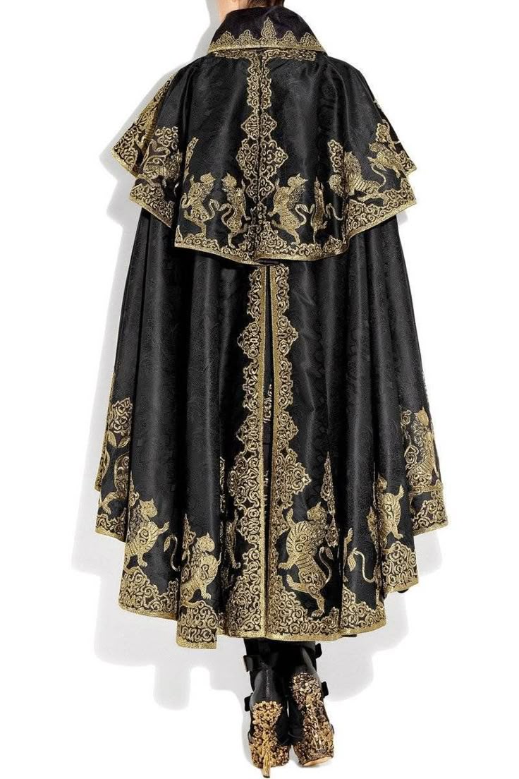 a black cape with elaborate gold embroidery, featuring ornate designs and stylized figures, is displayed on a person from the back view, coupled with matching embroidered boots.