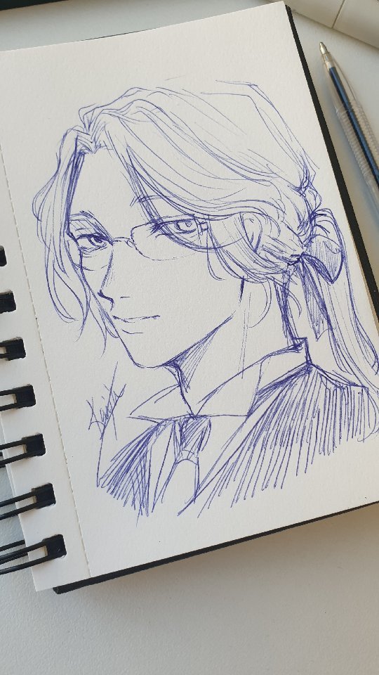closeup view of a pen sketch on a notebook. the drawing is a portrait of an animestyle character, likely male, with long hair pulled back into a ponytail. he's wearing glasses and a suit. the style is detailed and expressive, done in blue ink. a pen rests on the notebook next to the drawing. the background is a simple, offwhite surface.