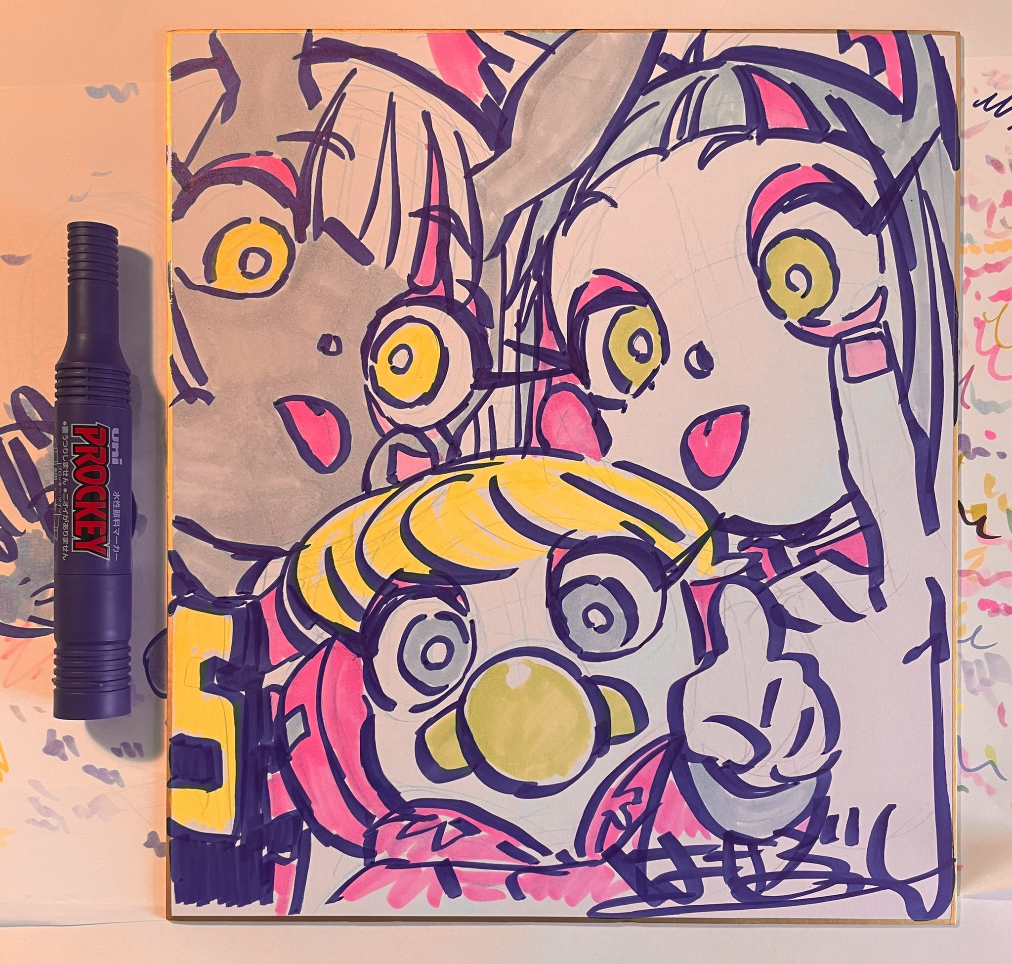 the image is a vibrant drawing of three stylized cartoon characters, likely inspired by anime or manga. they are drawn with bold black outlines and filled with bright colors, creating a playful and energetic feel. the characters have large, exaggerated eyes, a common characteristic of these styles. they are positioned close together, almost filling the entire frame, which enhances their expressive features. the presence of a purple marker leaning against the drawing suggests the artwork is freshly made and adds to the behindthescenes, creative atmosphere.
