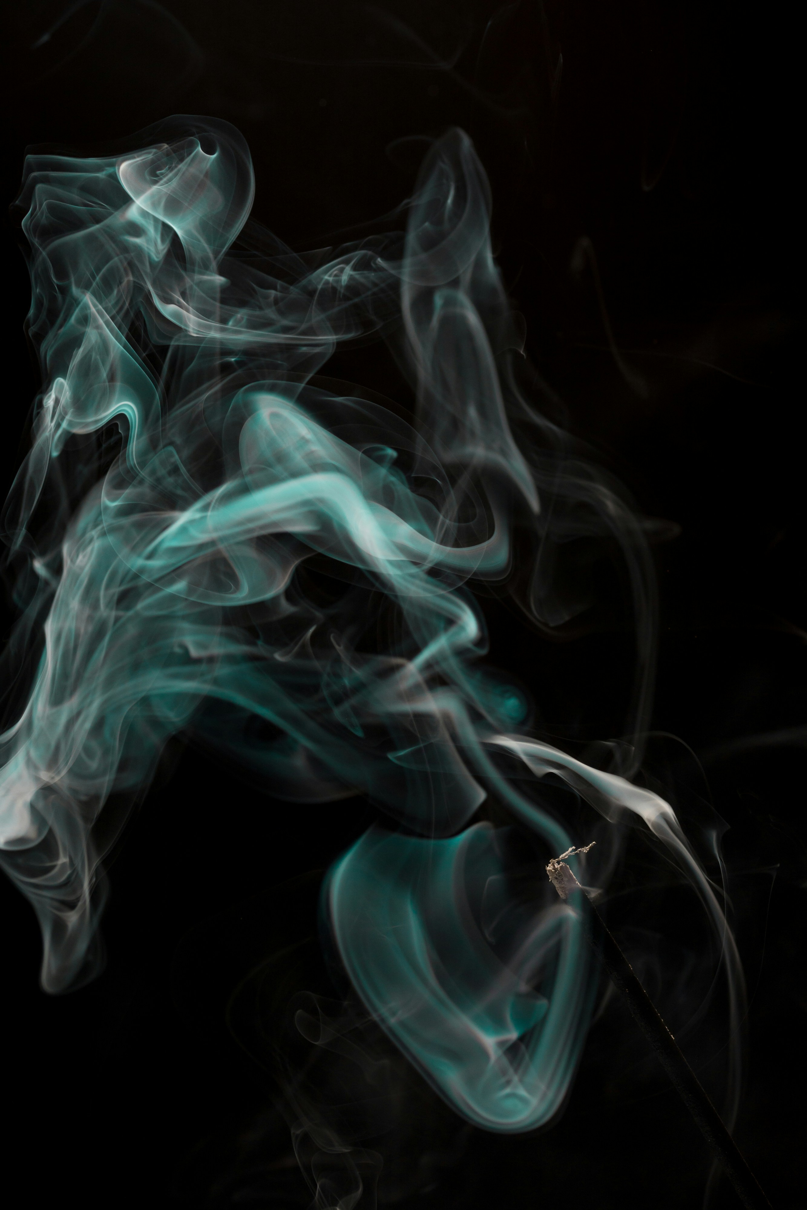 this is an abstract photograph of green and white smoke against a black background. the image has a mystical and ethereal quality, with the smoke forming swirling patterns that resemble clouds or ink in water.