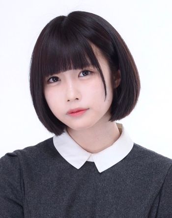 a portrait of a young asian woman with short black hair with bangs, wearing a white collar grey shirt, looking directly at the camera.