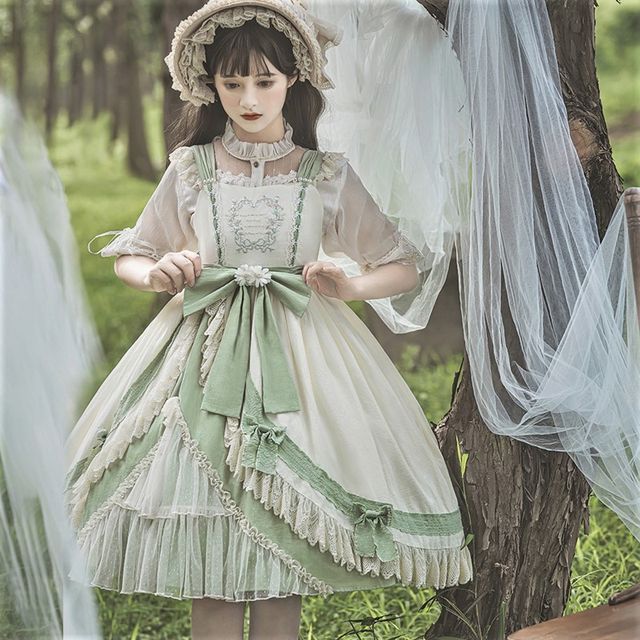 a young woman in a vintageinspired, romantic lolita dress poses in a forest setting. she wears a white and green dress with lace detailing, a matching hat, and her hair is styled in soft waves. the image has an ethereal and dreamy atmosphere.