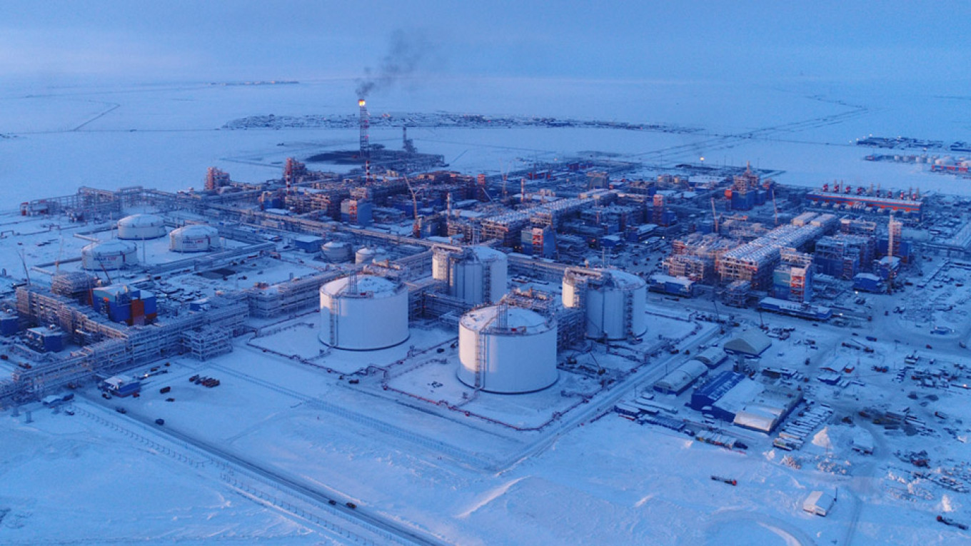 an aerial view of an industrial complex in a snowy, arctic landscape.  the complex, likely an oil refinery or natural gas processing plant, features numerous storage tanks, pipes, and other infrastructure.  construction is ongoing with cranes and equipment visible throughout the site.  the vast snowy tundra stretches out in the background, highlighting the remote location of this energy production facility.