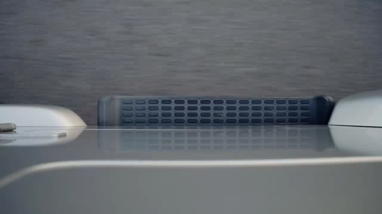 the image shows a closeup view of the top of a washing machine. the washing machine is silver and has a textured plastic surface. the image is taken from a low angle, looking up at the machine.