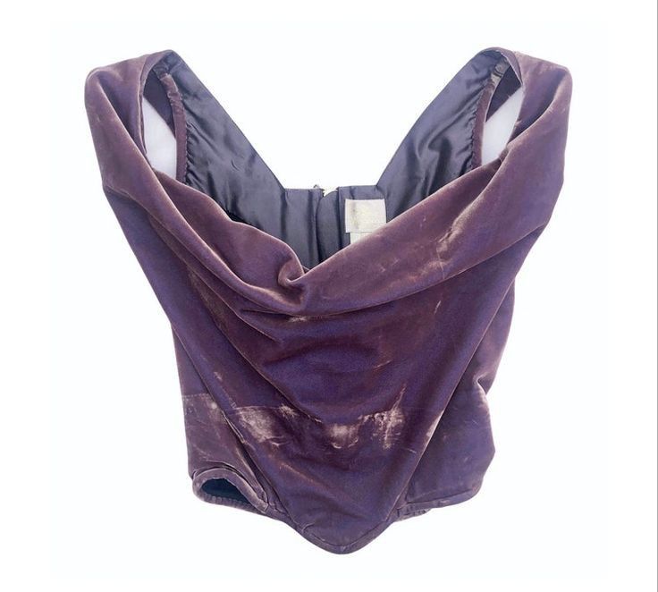 a purple velvet corset top with a vneckline is displayed against a white background. the top is sleeveless and features a draped design.
