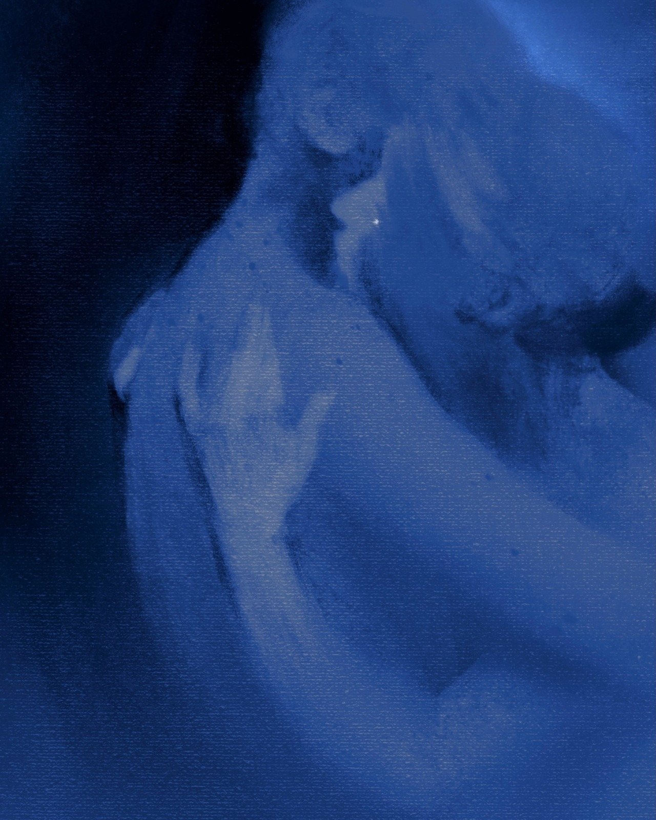 a closeup image of a woman with her face mostly obscured by shadow. the image has a blue monochrome palette.