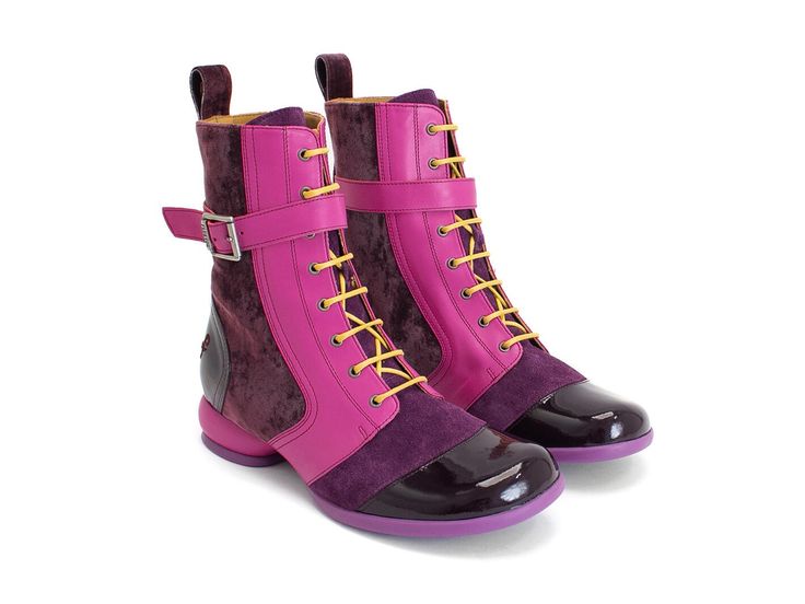 two pink and purple women's hightop ankle boots are displayed on a white background. the boots feature laceup fronts, a buckle strap, and a velvet and leather design.