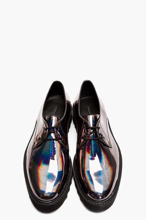 a pair of men's iridescent oxfords are displayed against a white background. the shoes are a dark, metallic color with a glossy, patent leather finish. the iridescence creates a rainbow effect on the shoes' surface. the shoes are laceup oxfords with a slightly chunky sole.