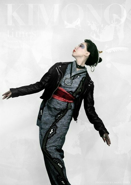 a fashion portrait featuring a model in a modern interpretation of a traditional japanese kimono, paired with a black leather jacket. the model is styled with traditional hair ornaments and a red obi, set against a blurred backdrop with the words "kimono times" subtly visible. the overall aesthetic blends classic japanese elements with contemporary fashion.