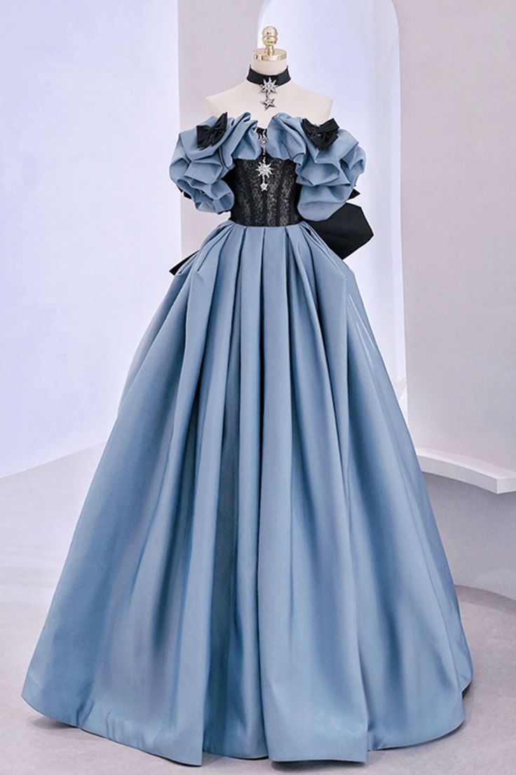 a fulllength image of a light blue ball gown on a mannequin in front of a white wall. the dress is offtheshoulder with large ruffles on the bodice and a black lace inset. the skirt is full and flowing. the bodice is fitted with a laceup back. the dress is accessorized with a black ribbon at the waist.
