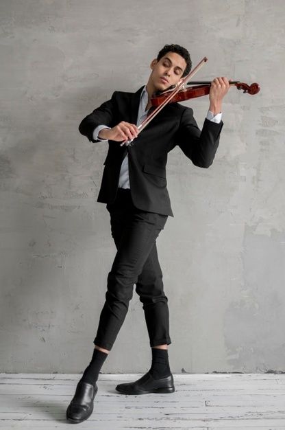 a young man dressed in a black suit stands against a textured gray wall, his eyes closed as he plays the violin. he holds the instrument with grace and concentration, the bow drawn across the strings. the soft lighting creates a sense of intimacy and highlights the elegance of his posture and the emotion in his performance.