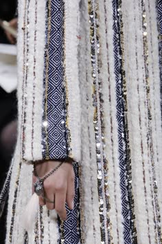 a closeup shot of white tweed fabric with sequins and a diamond pattern. the fabric has a luxury and vintage feel. the texture of the fabric is visible, and the sequins add sparkle to the garment. the photo is taken from a closeup perspective and the focus is on the fabric.