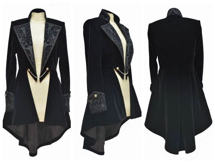 three images of a black velvet gothic tailcoat. the coat has a high collar, decorative trim on the collar and cuffs, buttons with chain detail, and a highlow hem. the first image shows the front view of the coat, the second image shows the side view, and the third image shows the back view. the coat is worn over a light colored top.