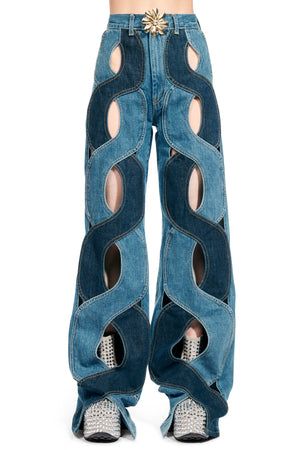 a model is wearing a pair of highwaisted jeans with a cutout design. the jeans are a light blue denim and have a dark blue denim design. the model is posing with their legs slightly apart. they are wearing sparkly shoes.