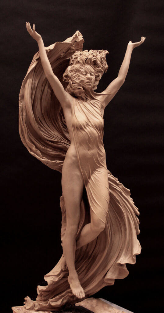 the image showcases a stunning clay sculpture of a woman caught in middance. her arms are raised above her head, and her body is gracefully arched. a flowing fabric wraps around her, mimicking the movement of her dance and adding to the sense of dynamism. the sculpture is set against a simple black background, which serves to highlight the artistry and details of the piece.  the lighting is soft and dramatic, emphasizing the curves and contours of the woman's form.