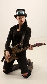 a woman in steampunk attire kneels while shredding on an intricately carved electric guitar.