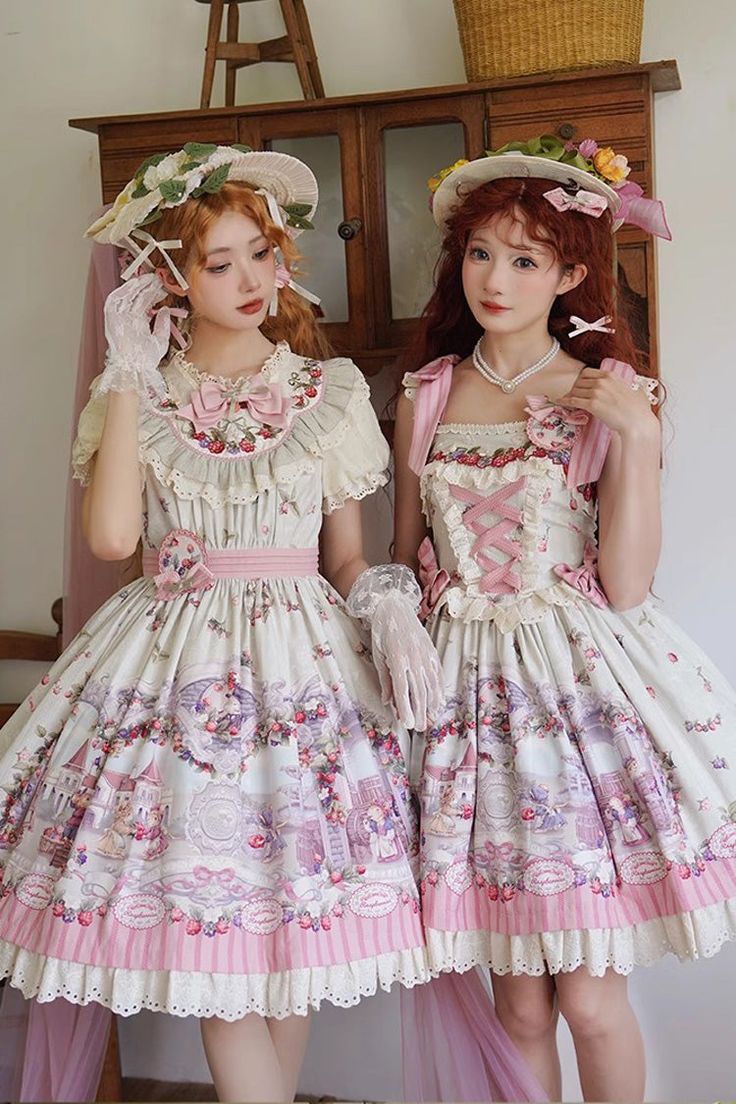 two women are modeling lolita fashion dresses in a studio setting. the dresses are primarily white with pink accents and floral and strawberry patterns. both women are wearing large straw hats and white gloves.