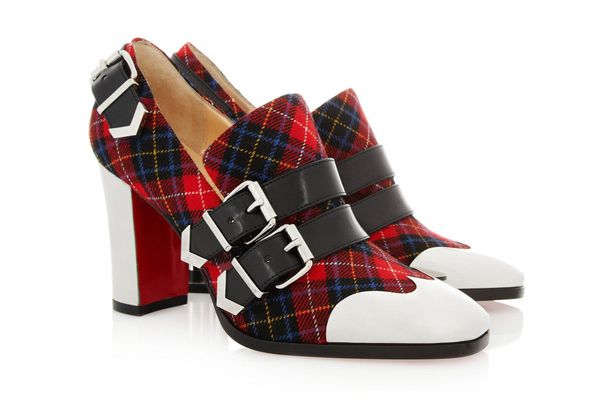 a closeup shot of a pair of christian louboutin women's highheeled ankle boots. the shoes are made of red plaid fabric with black leather double buckles and white leather toe caps.  they feature a chunky red and white heel, typical of the brand's signature style. the shoes are positioned on a white background, slightly angled to show both shoes.