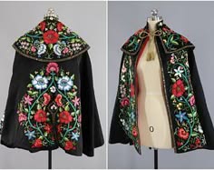 the image shows two black embroidered cloaks. both are made of a black fabric with colorful floral patterns. the flowers are white, red, green, and yellow. the cloaks are lined with white fabric and have a red trim. the cloaks are hanging on mannequins, and the image is cropped so that only the cloaks are visible.