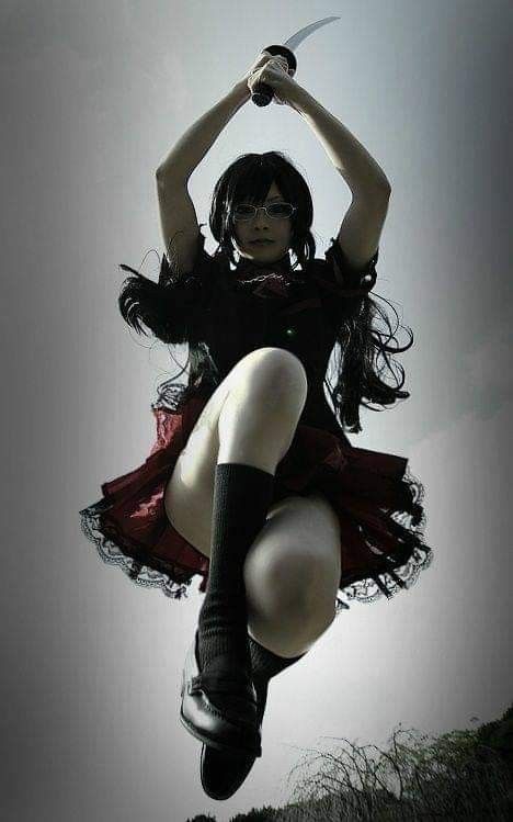 a woman is standing in the air holding a katana above her head. she is wearing a black dress and red skirt. she is looking serious and determined. her hair is dark and her eyes are piercing.