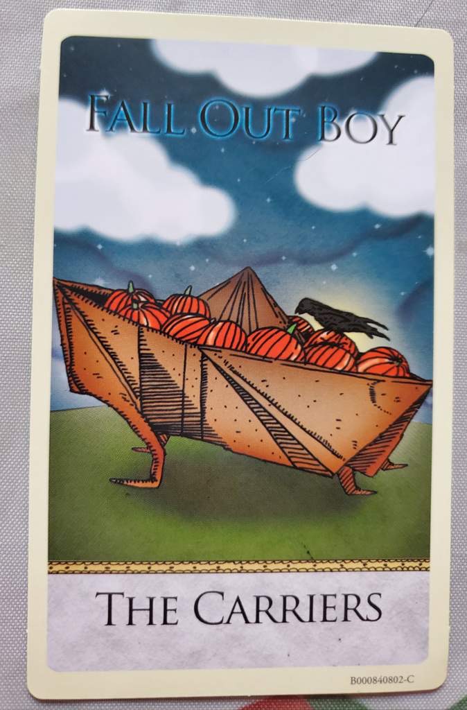 an image of fall out boy's album cover, "the carriers". the image is a cartoon illustration of an origamilike boat, filled with pumpkins, flying through the night sky. the background is a dark blue with white clouds, stars, and a moon. the title of the album, "the carriers," is printed at the bottom of the image. the band's name, "fall out boy," is printed at the top of the image.