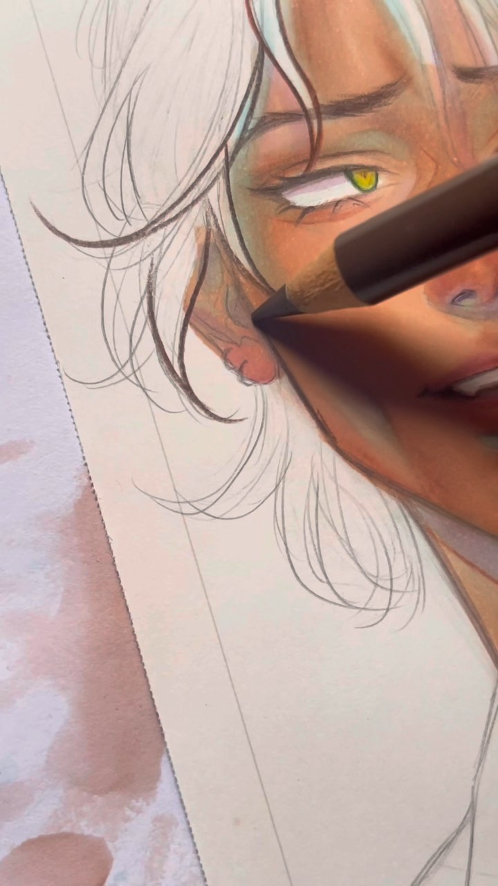 a closeup shot shows a digital artist's hand using a colored pencil to add color and detail to a character's eye in a drawing. the character has lightcolored hair and tan skin. the drawing is done on paper with visible pencil lines.  the focus is on the eye and the process of adding color, highlighting the texture and precision of the artist's work. the overall style is fantasyesque, with the character having an expressive look.