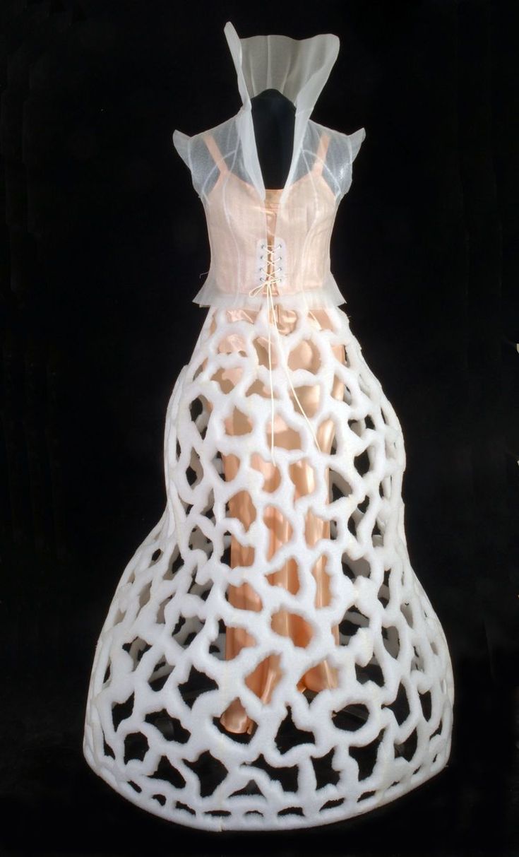 a stunning white dress with a sheer lace bodice and a voluminous, intricate skirt. the skirt is made of a netlike material that creates a unique and dramatic silhouette. the dress is modern, avant garde, and looks like a sculpture of lace.