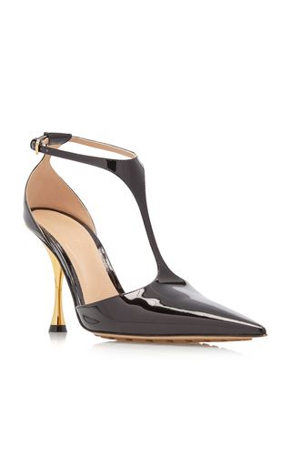 a pair of black patent leather pointytoe pumps with a gold heel. the shoes have a tstrap design.  they are stylish and elegant, perfect for a formal occasion or evening wear.