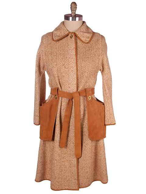 a long, tweed coat is displayed on a mannequin. the coat is tan and brown, and it has long sleeves, a collar, and a belt. the coat also has two brown leather pockets.