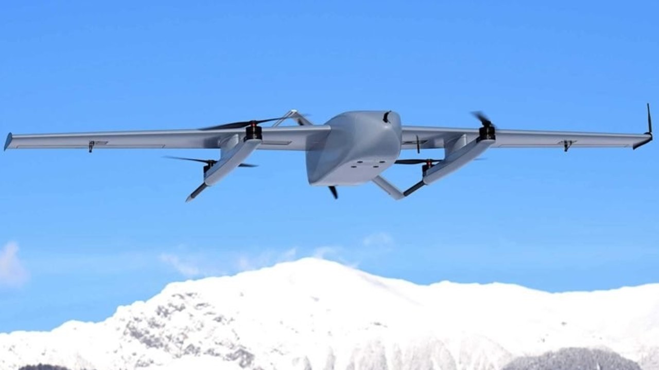 a drone, a type of unmanned aerial vehicle, flies against a clear blue sky with snow covered mountains in the background. the drone is in flight, with its wings spread wide and propellers spinning. the drone has a gray body and appears to be designed for surveillance or reconnaissance purposes. the photo was taken during the winter, as evidenced by the snowy mountains in the background.